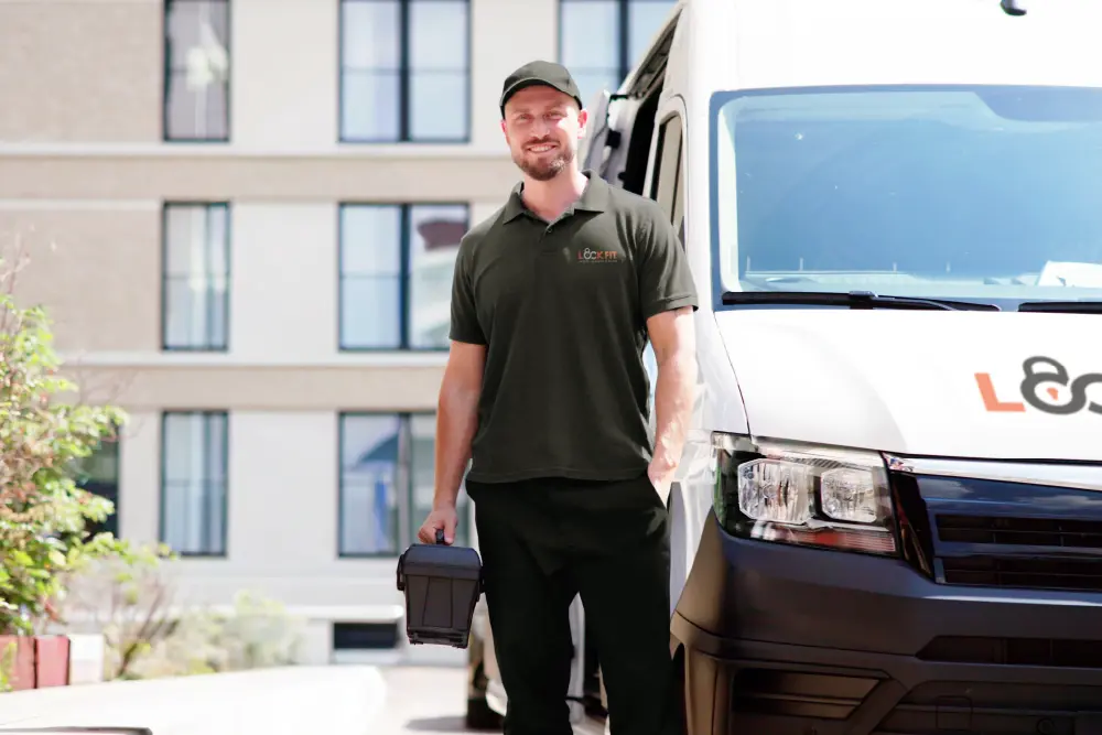 Trusted LockFit locksmith technician with professional equipment standing confidently beside service vehicle in residential area